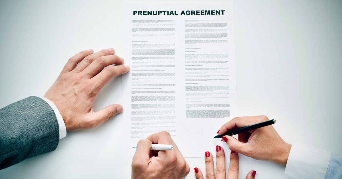 A man and woman signing a prenuptial agreement document 