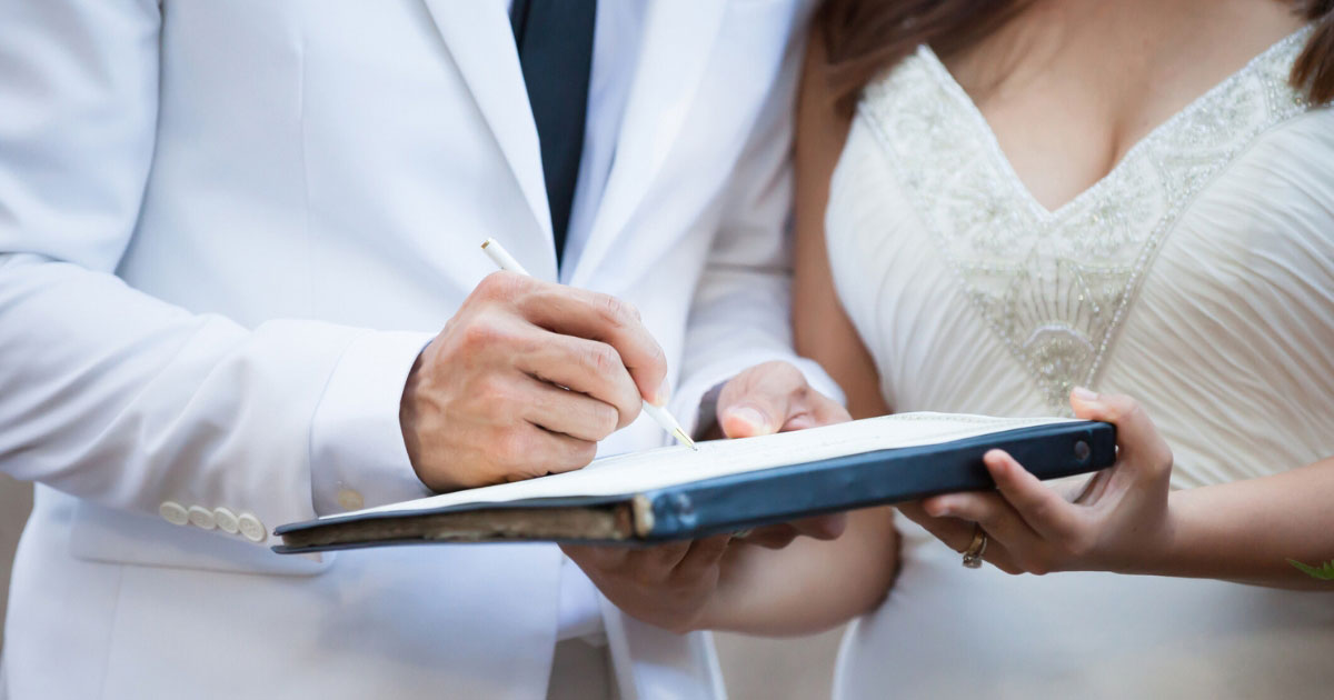man and woman signing a prenuptial agreement